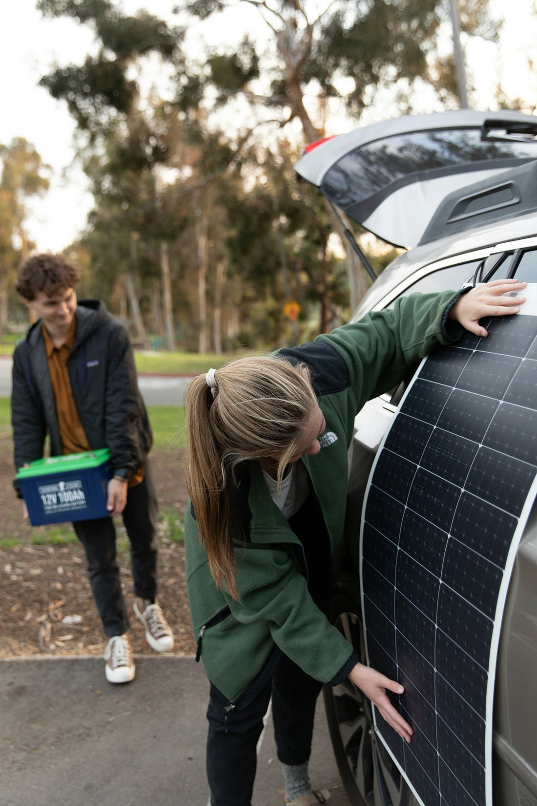 two people standing next to a car with a solar panel on it