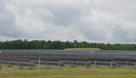 Solar panels generate power beneath a cloudy sky.