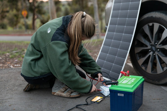 a woman working on a solar panel in front of a car