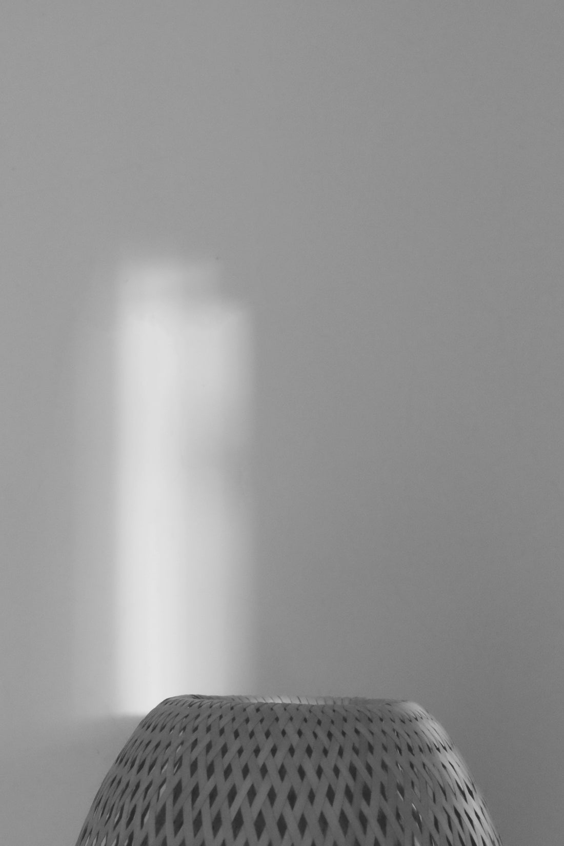 a black and white photo of a light coming through a window