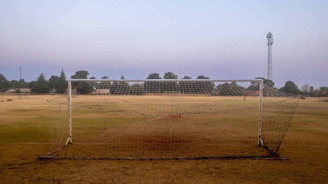 A soccer goal in a field with a sky background