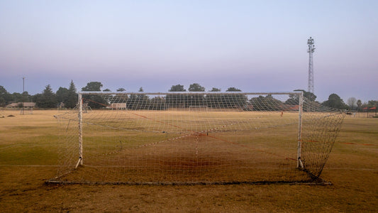 A soccer goal in a field with a sky background