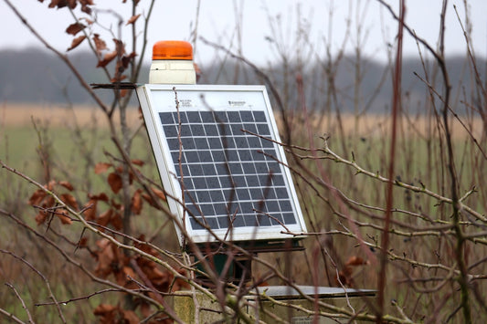 A solar panel mounted to a pole in a field
