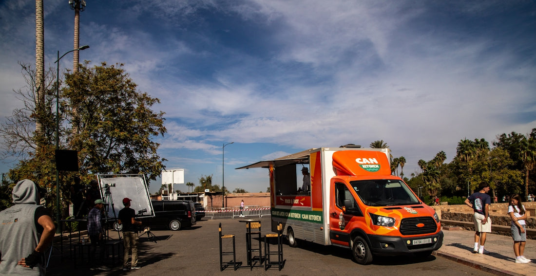 An orange food truck parked outdoors on a sunny day.