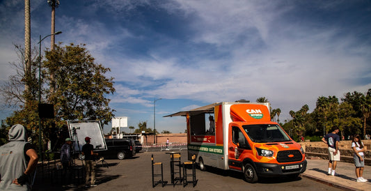 An orange food truck parked outdoors on a sunny day.